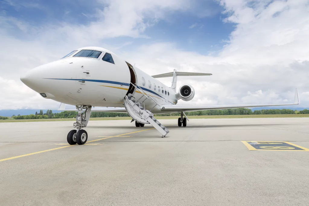 Gulfstream G550 aircraft with registration number OE-ISN parked on an airport tarmac, featuring the jet's front view with boarding stairs extended.