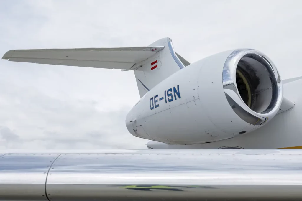 Close-up view of the engine and tail section of a Gulfstream G550 aircraft with registration number OE-ISN, showcasing its sleek design against a cloudy sky.