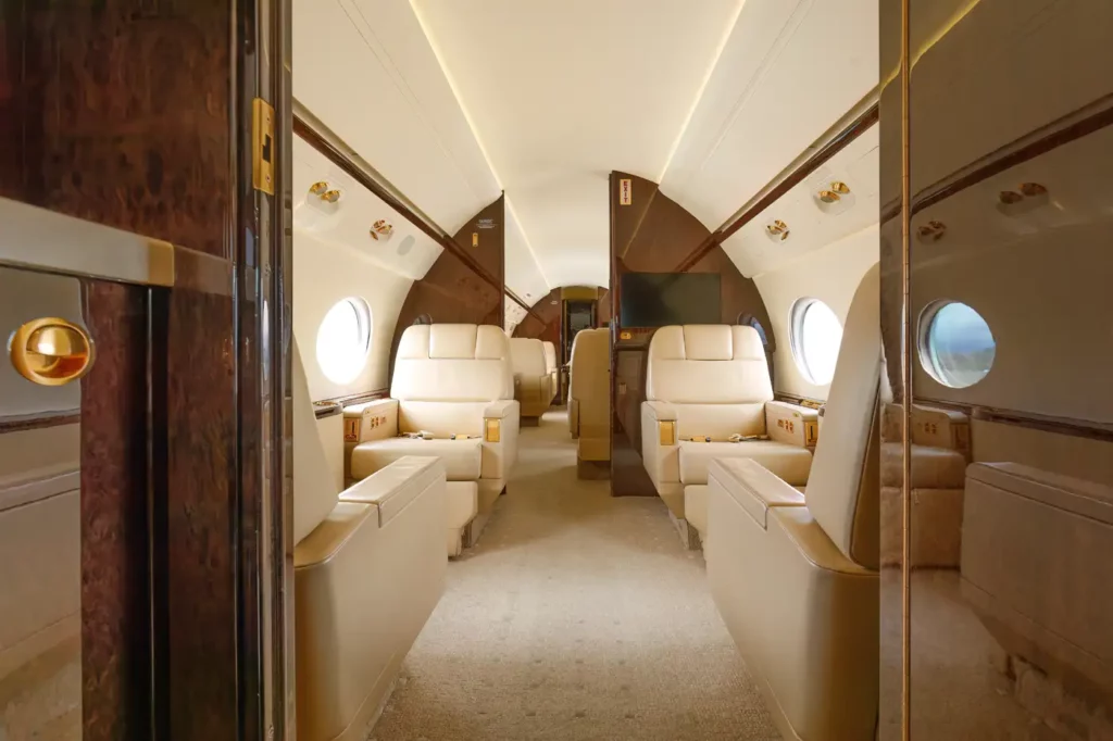 Interior shot of the forward cabin in the Gulfstream G550, featuring luxurious leather seats and ambient lighting, with the cockpit visible in the background.