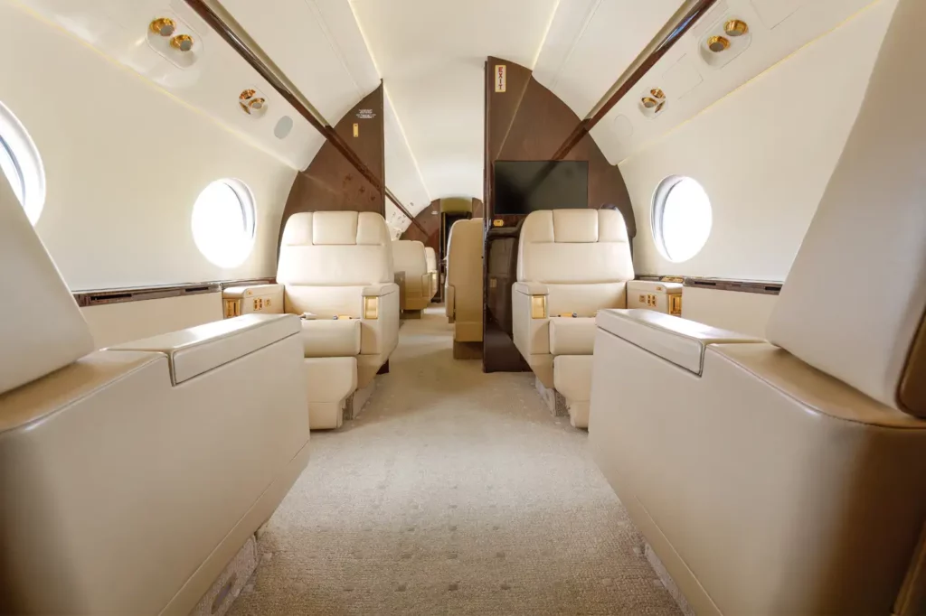 Mid-cabin view of the Gulfstream G550, showcasing plush leather seats, ambient lighting, and a central aisle leading to the forward section of the aircraft.