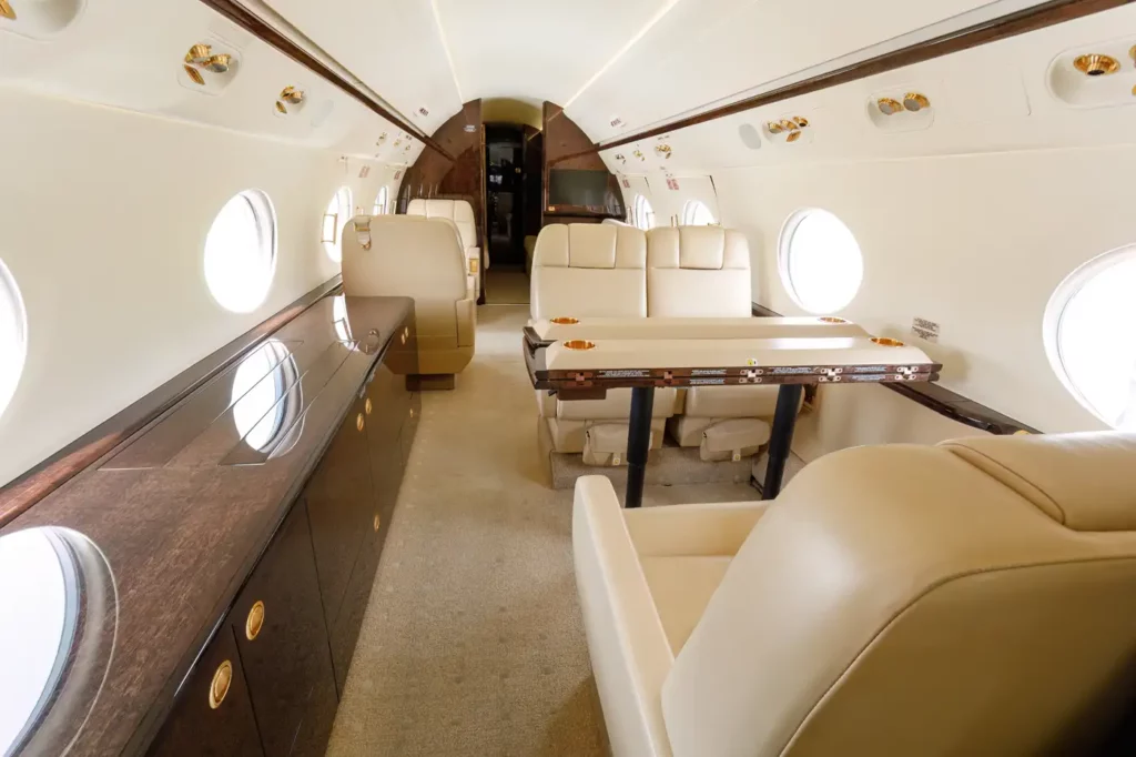 View from the mid-cabin towards the aft of the Gulfstream G550, featuring luxurious seating and spacious layout with large windows.