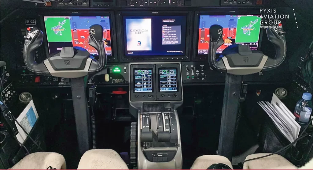 Cockpit of a Cessna Citation CJ3 featuring dual control yokes, multiple display screens with flight information, and advanced avionics, providing a modern and high-tech piloting environment.