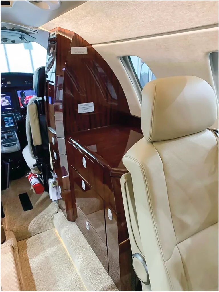 Side view of the galley in a Cessna Citation CJ3, showing detailed woodwork and storage options, emphasizing the luxury and practicality of the aircraft's interior.