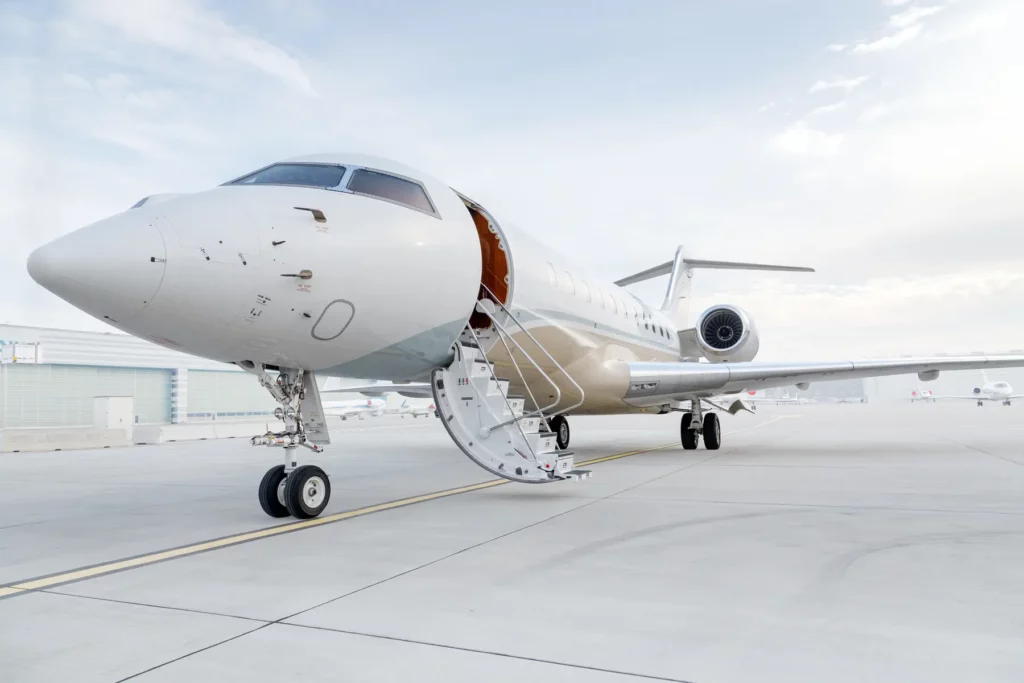 Bombardier Global 5000 jet with its stairs extended, positioned on an airport tarmac for boarding.