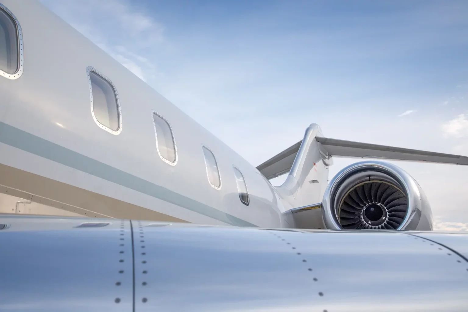 Close-up view of the engine and wing of a Bombardier Global 5000 jet against a clear sky.