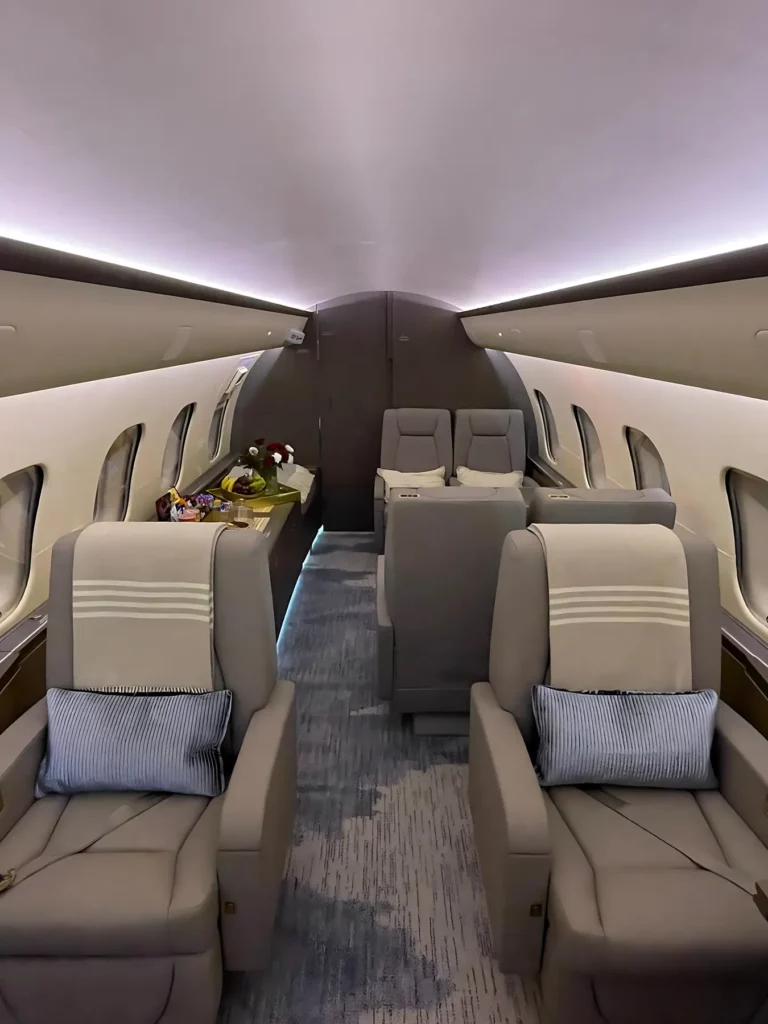 Mid-cabin view of a Bombardier Global 5000 jet featuring spacious seating and a credenza with refreshments.