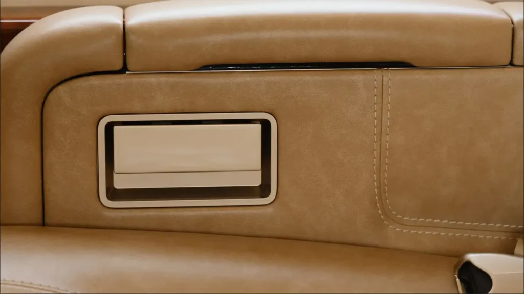 Detail of Gulfstream G500’s armrest and seat panel in tan leather with storage compartment