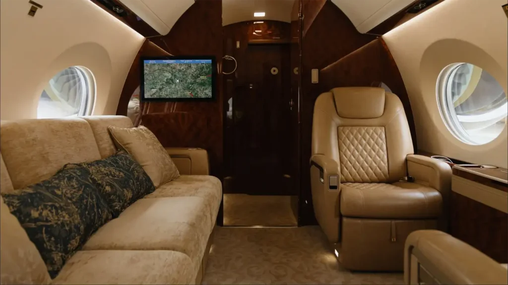 Interior of the Gulfstream G500 with leather seating and a sofa, showcasing the spacious cabin and in-flight entertainment system