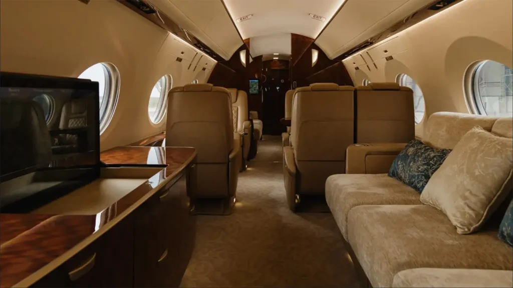 Gulfstream G500 cabin with a beige sofa and decorative pillows, showcasing luxurious and comfortable seating