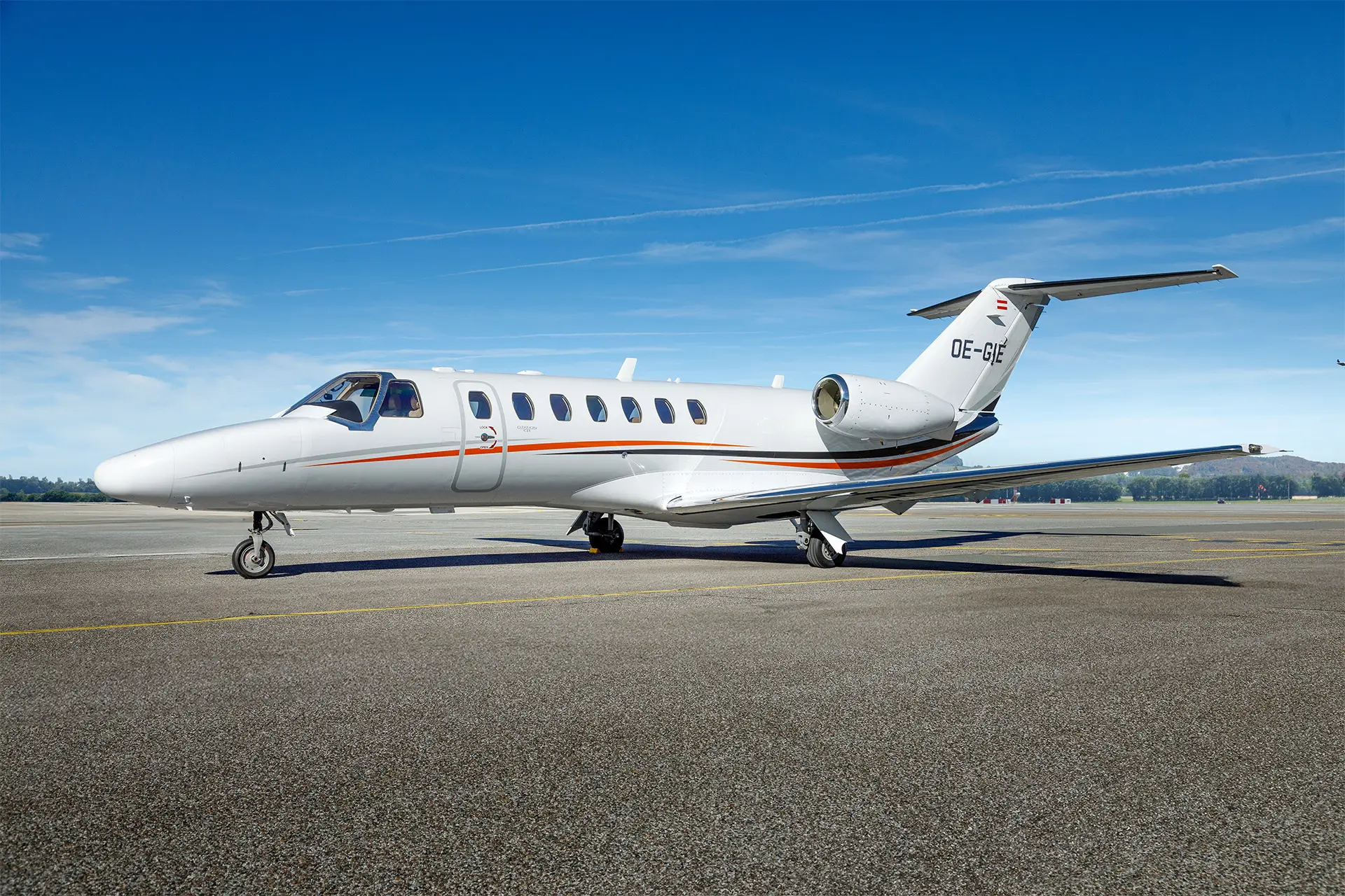 Cessna CJ3 aircraft with registration number OE-GIE parked on an airport tarmac, featuring the jet's side view