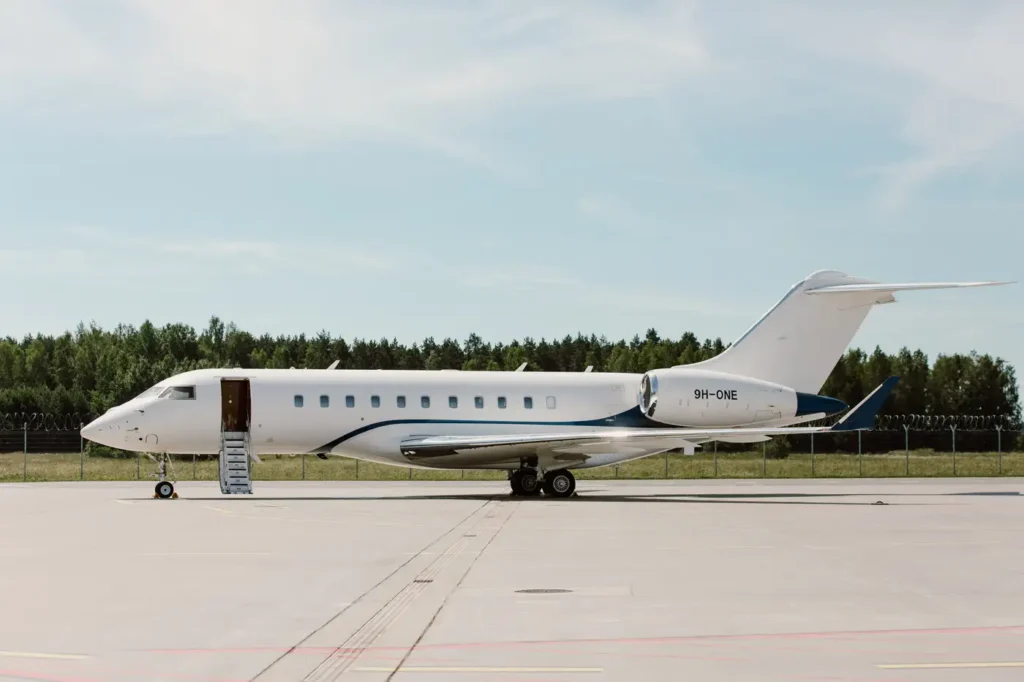 Full side view of Bombardier Global 5000 private jet parked on the runway with boarding stairs extended