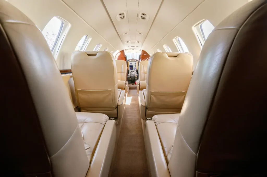 View of the cabin interior of a Cessna Citation CJ3 private jet, showing beige leather seats and windows