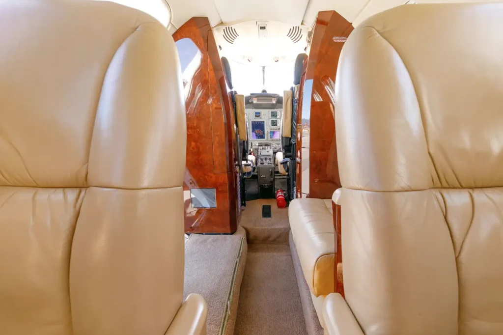 View from the cabin towards the cockpit of a Cessna Citation CJ3 private jet with leather seating and wood accents