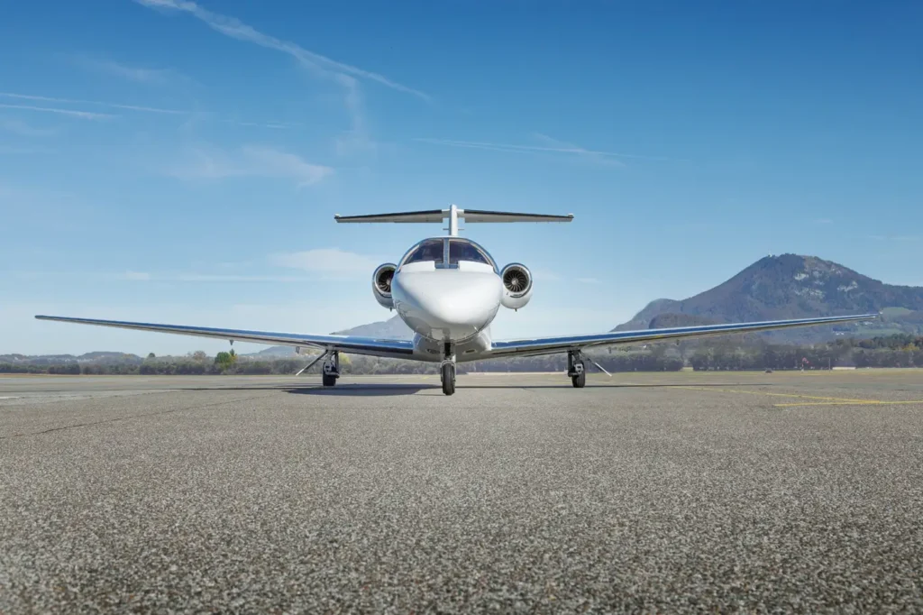 Front view of Cessna Citation CJ3 private jet OE-GIE parked on the runway with mountains in background