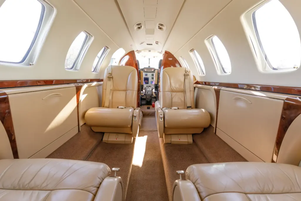 Interior view of a Cessna Citation CJ3 private jet cabin with beige leather seats and wood panelling