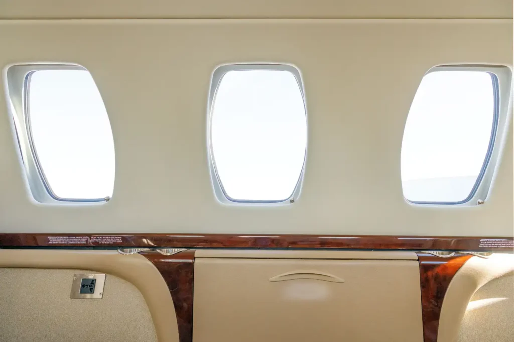 Row of windows inside Cessna Citation CJ3 private jet cabin with beige leather finishes