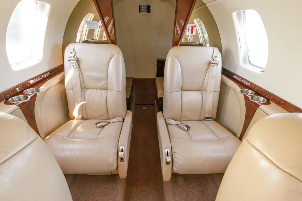 Two beige leather seats with cup holders in the cabin of a Cessna Citation CJ3 private jet