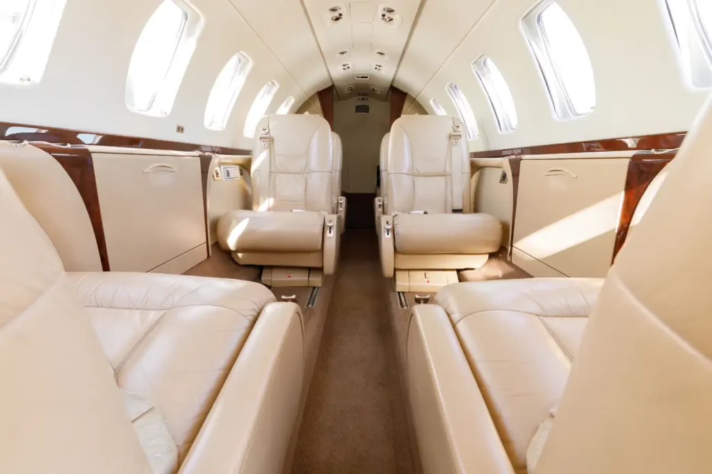 Full view of the seating arrangement inside a Cessna Citation CJ3 private jet with beige leather seats and windows