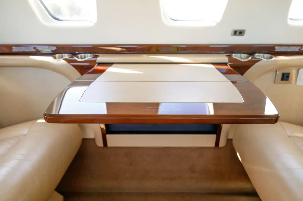 Folding wooden table and beige leather seats in the cabin of Cessna Citation CJ3 private jet