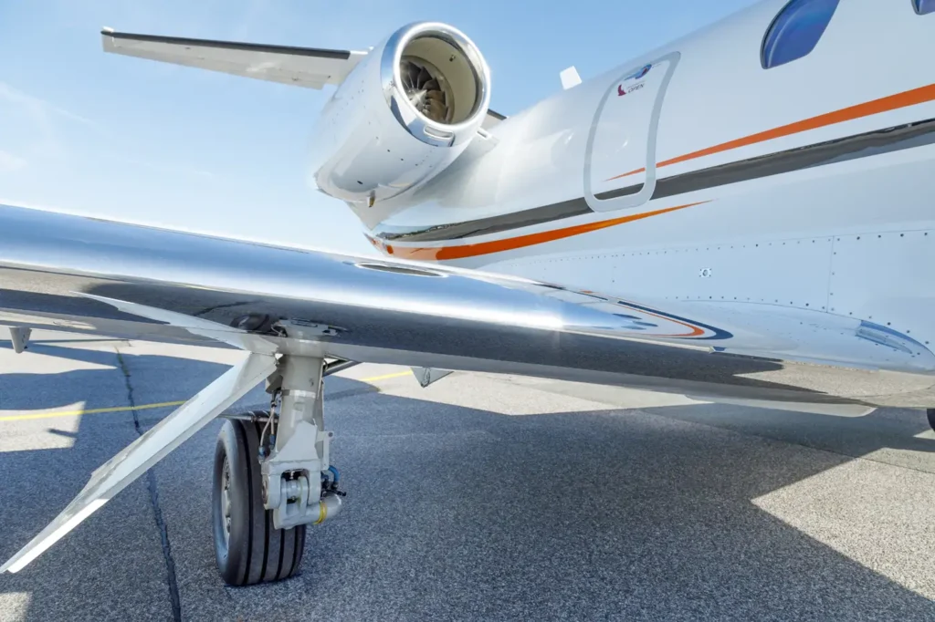 Close-up of Cessna Citation CJ3 landing gear and engine with reflective fuselage