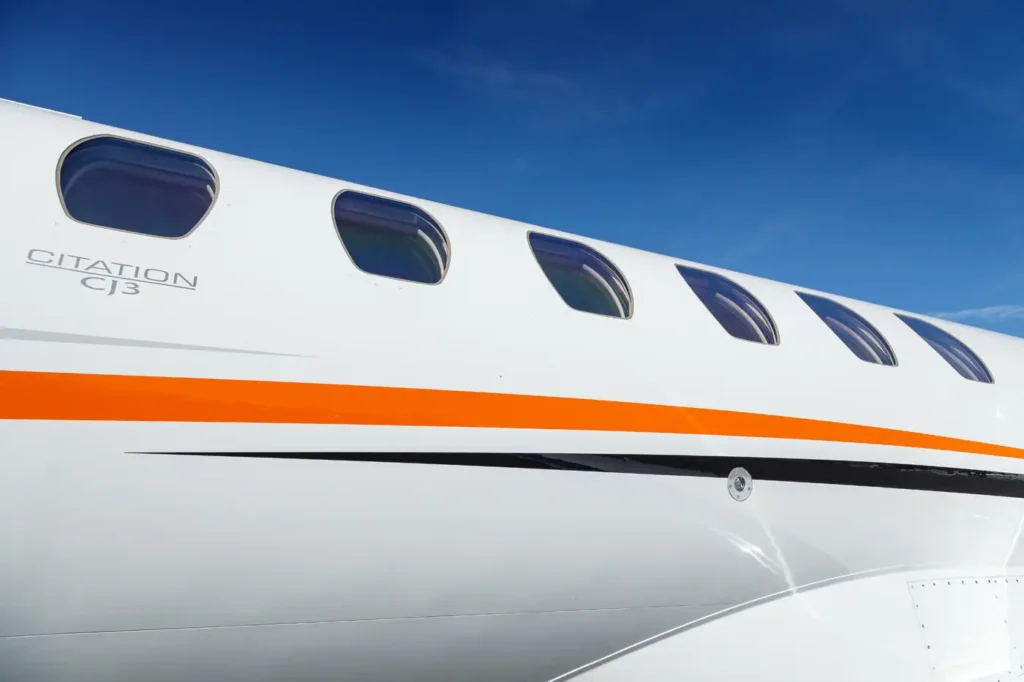 Side view of Cessna Citation CJ3 fuselage showing windows and logo under blue sky