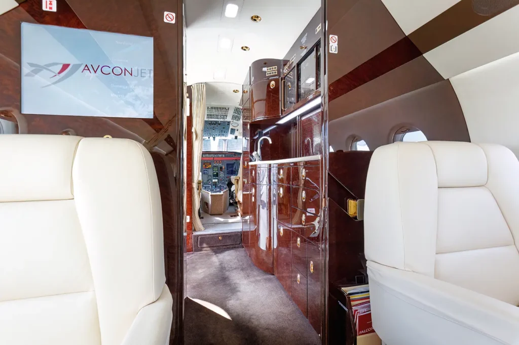 Galley area inside the Dassault Falcon 2000 private jet, featuring polished wood cabinetry, storage compartments, and luxury finishes for catering preparation.