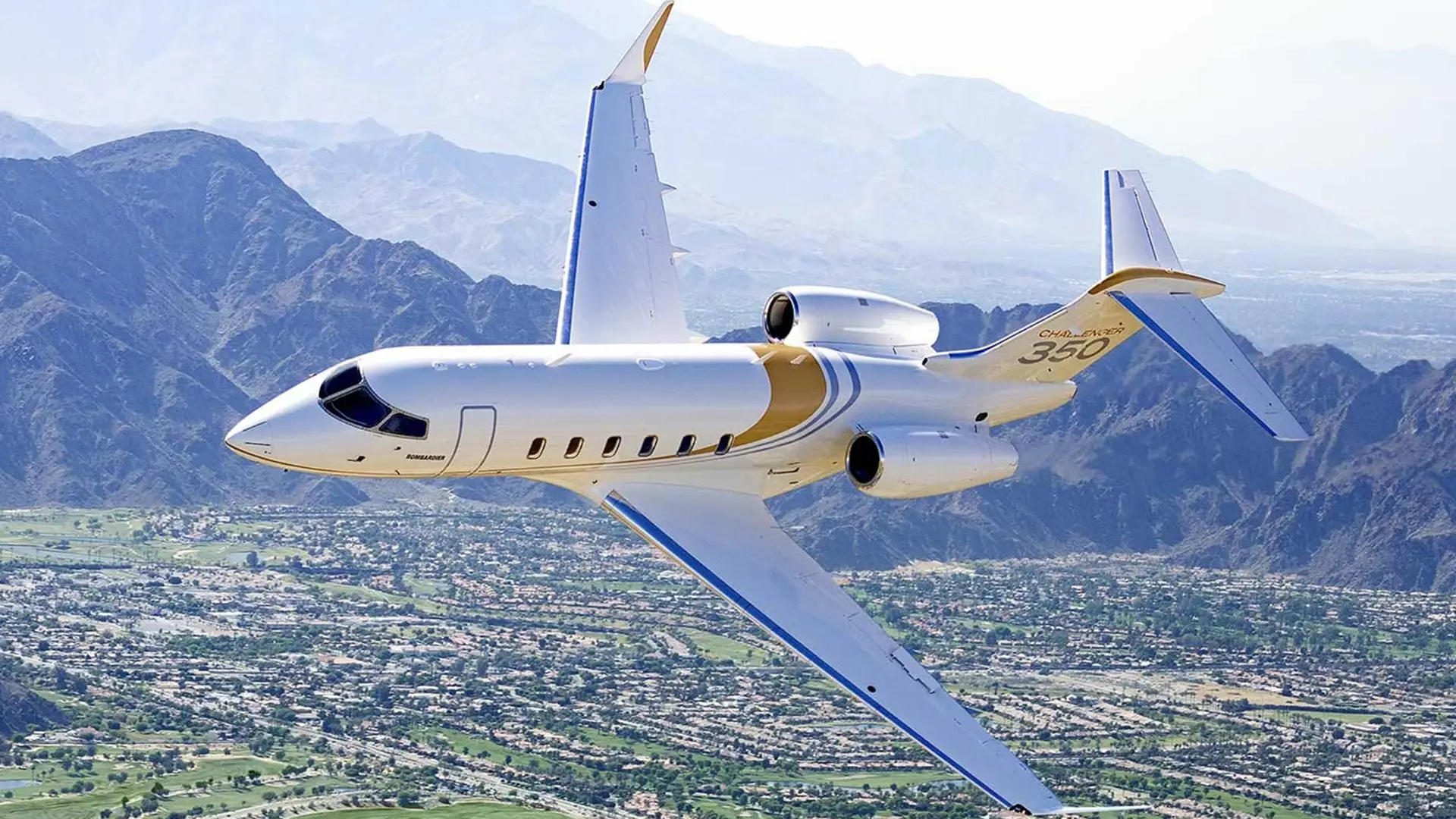 bombardier challenger 350 in flight with mountains in the background